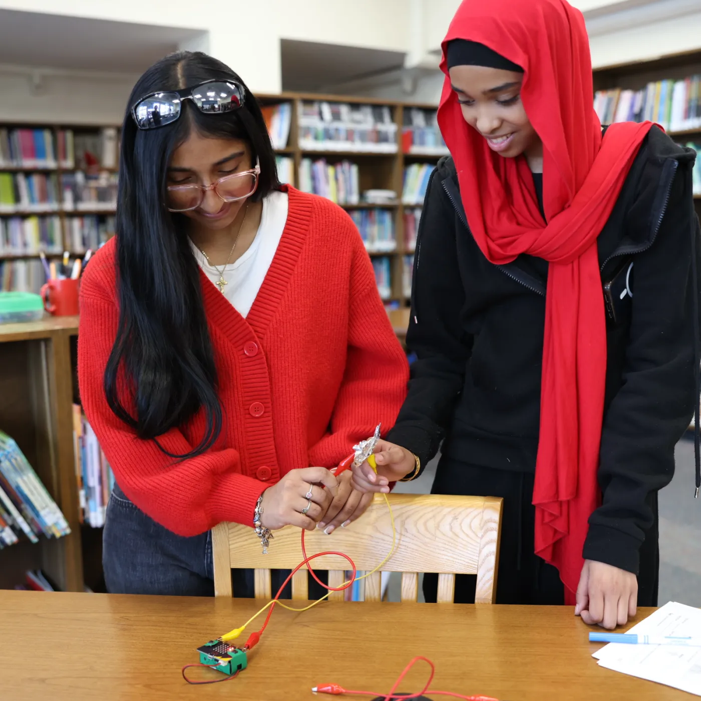 Two girls holding electrical leads on a micro:bit.