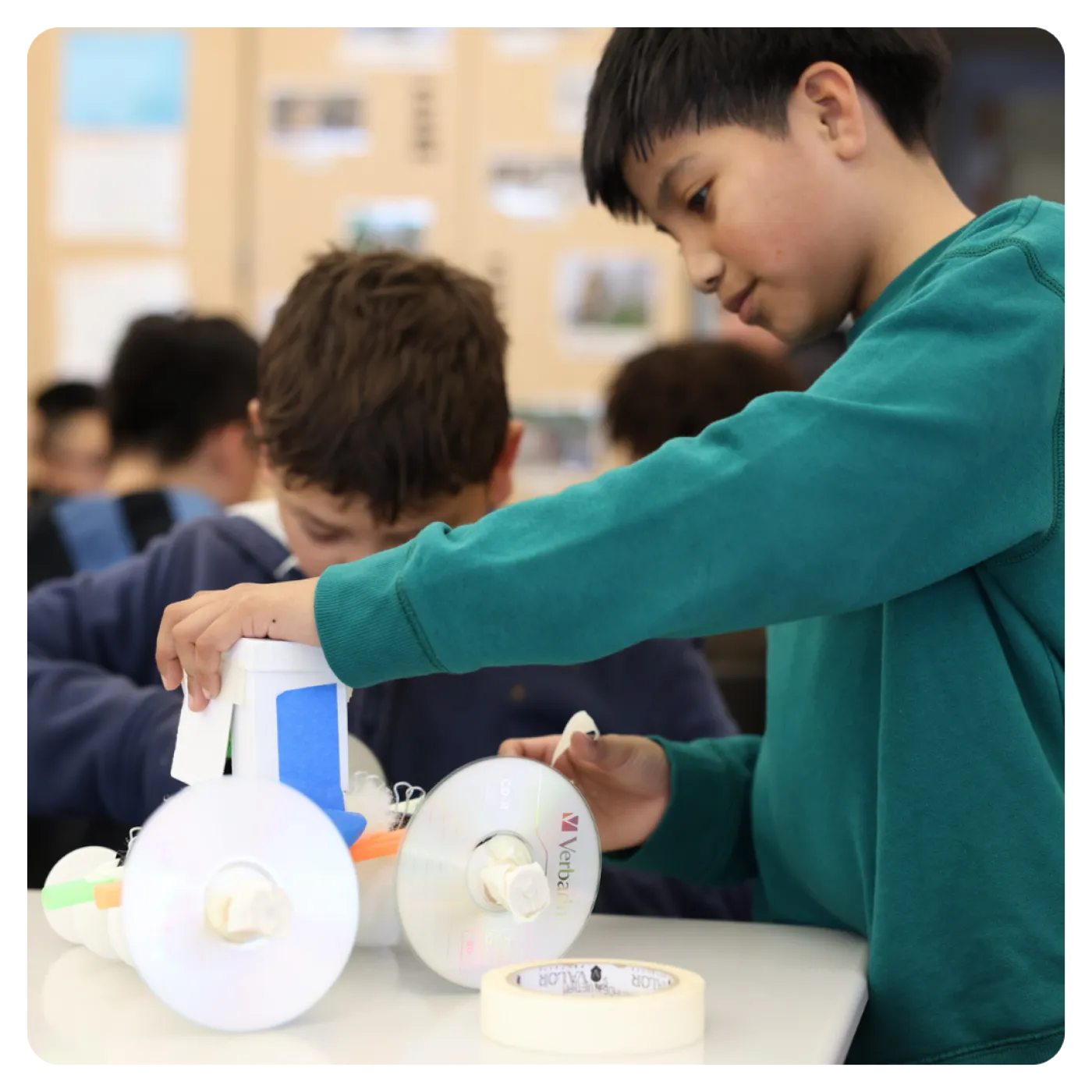 Two students building an upcycled toy vehicle.